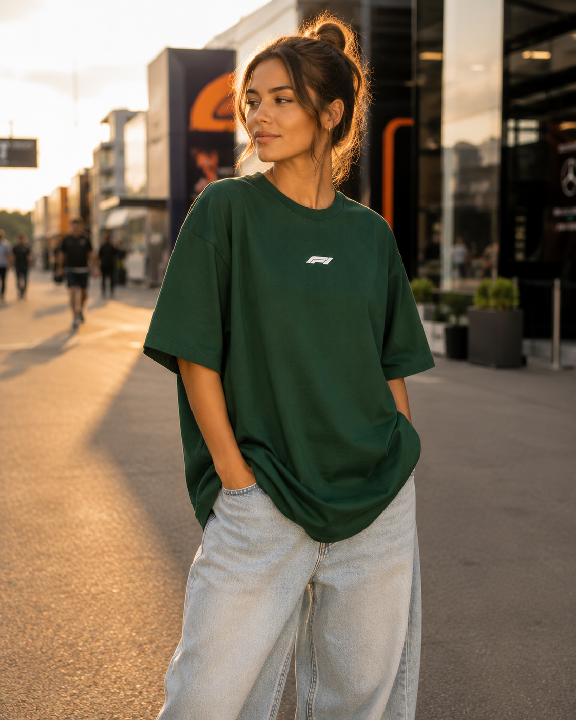 Woman wearing a green oversized t-shirt with a logo, standing on a street.
