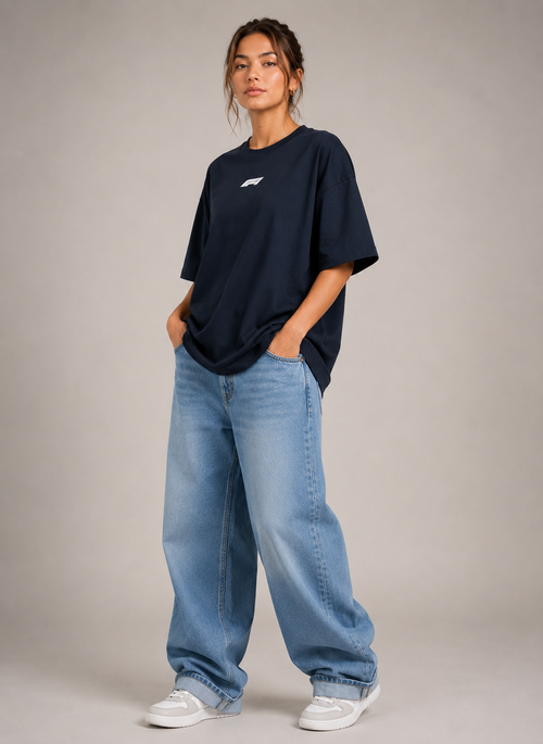 Person wearing a navy oversized t-shirt and light blue jeans on a plain background