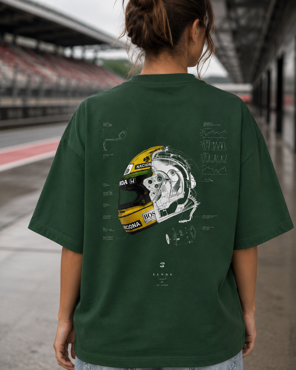 Person wearing a green t-shirt with a helmet design on the back, standing on a race track.