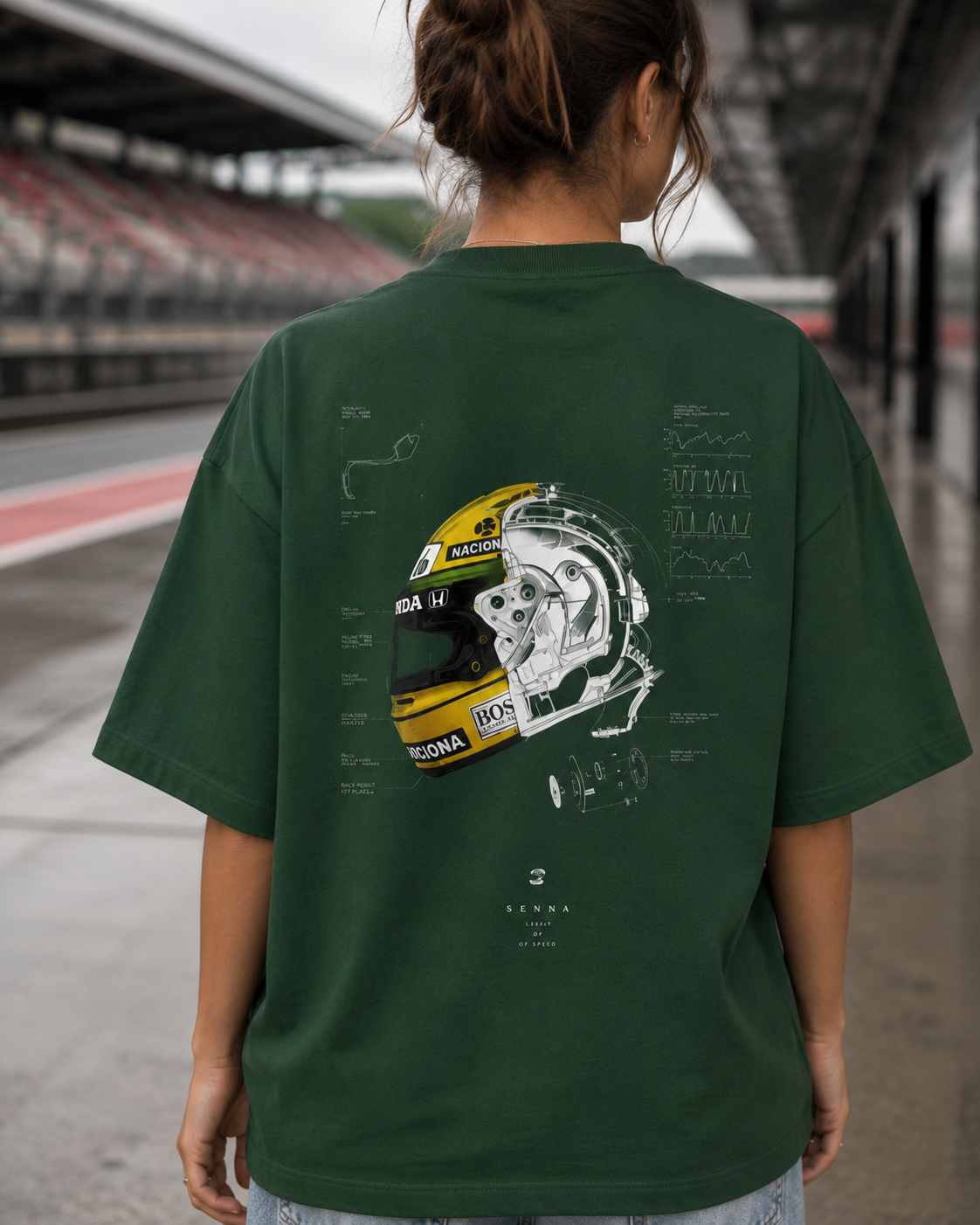 Person wearing a green t-shirt with a helmet design on the back, standing on a race track.
