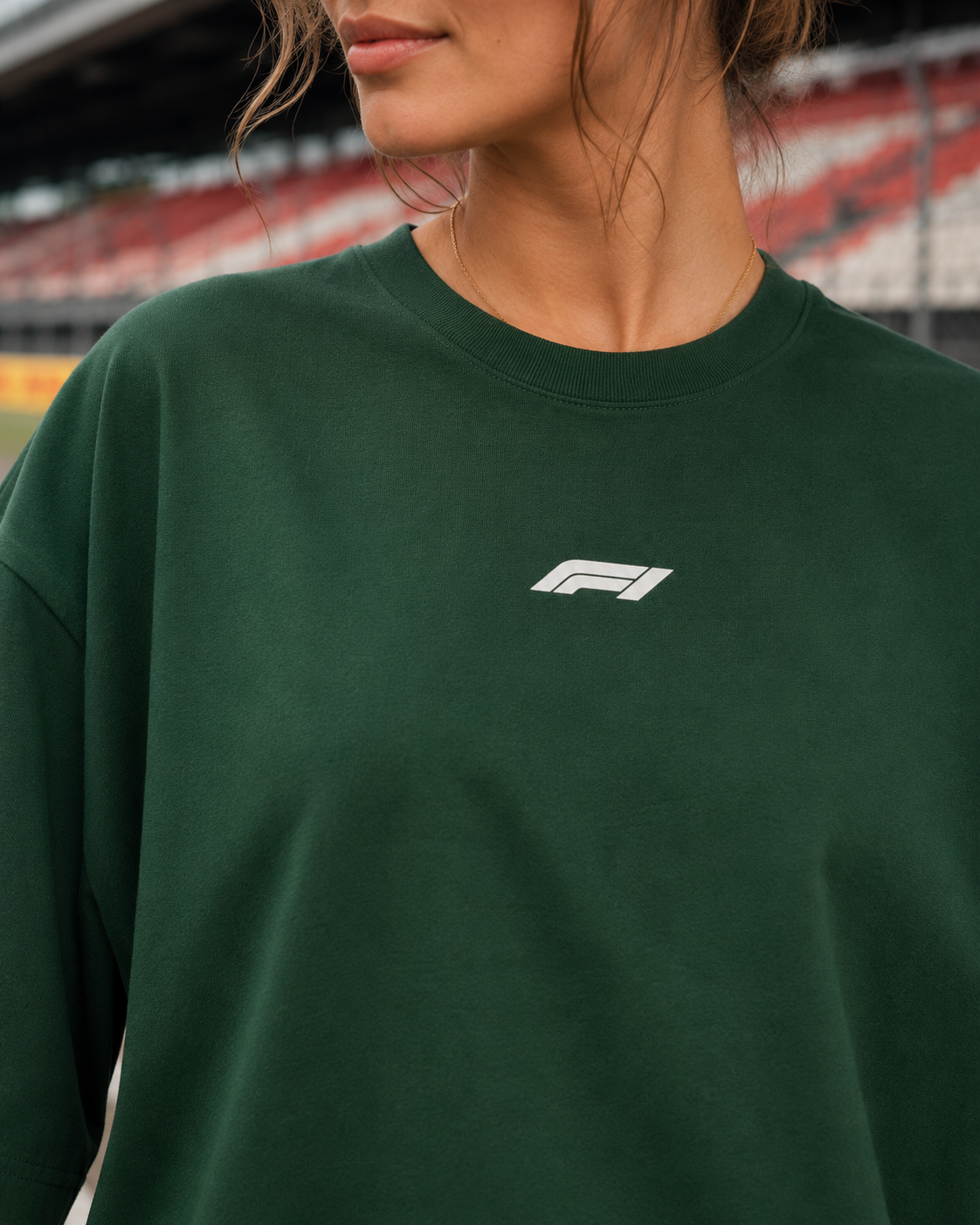 Person wearing a green sweatshirt with a logo in an outdoor setting